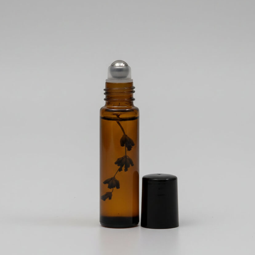 Brown glass roller bottle with black cap on a white background