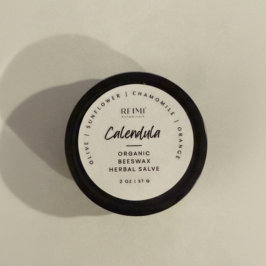 Container of REIMI Calendula Organic Beeswax Herbal Salve with a black lid on a light background.