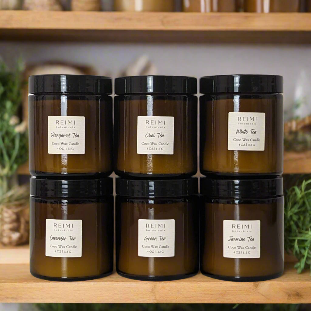 Six 4 ounce amber glass jars filled with coconut wax candles, white labels and black tops