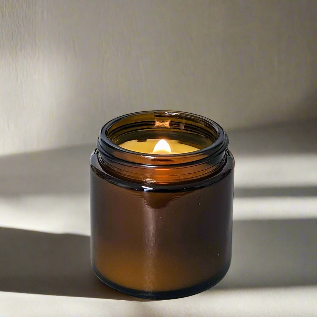 candle in amber glass vessel, wooden wick with flame