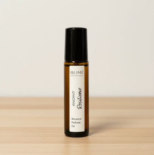 Bottle of Reimi Botanical Perfume Oil on a wooden surface with a light background