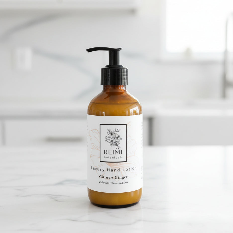 Brown bottle of Reimi Botanicals hand lotion on a wooden surface with a striped fabric background.