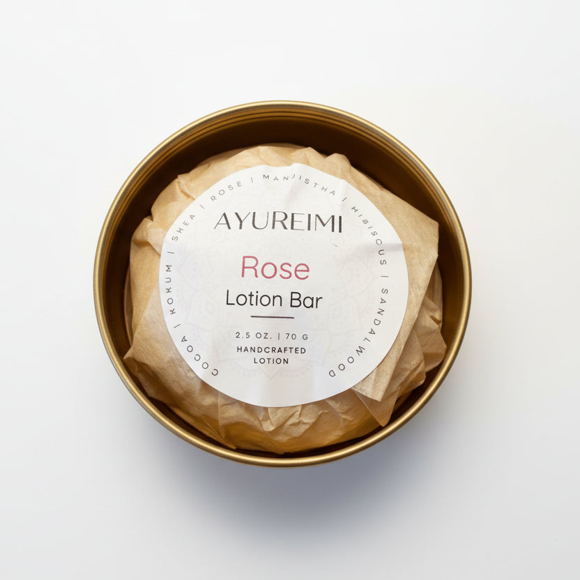 Rose lotion bar in a gold container with a visible label on a textured surface