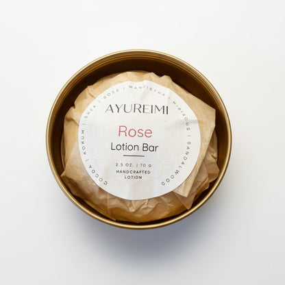 Rose lotion bar in a gold container with a visible label on a textured surface
