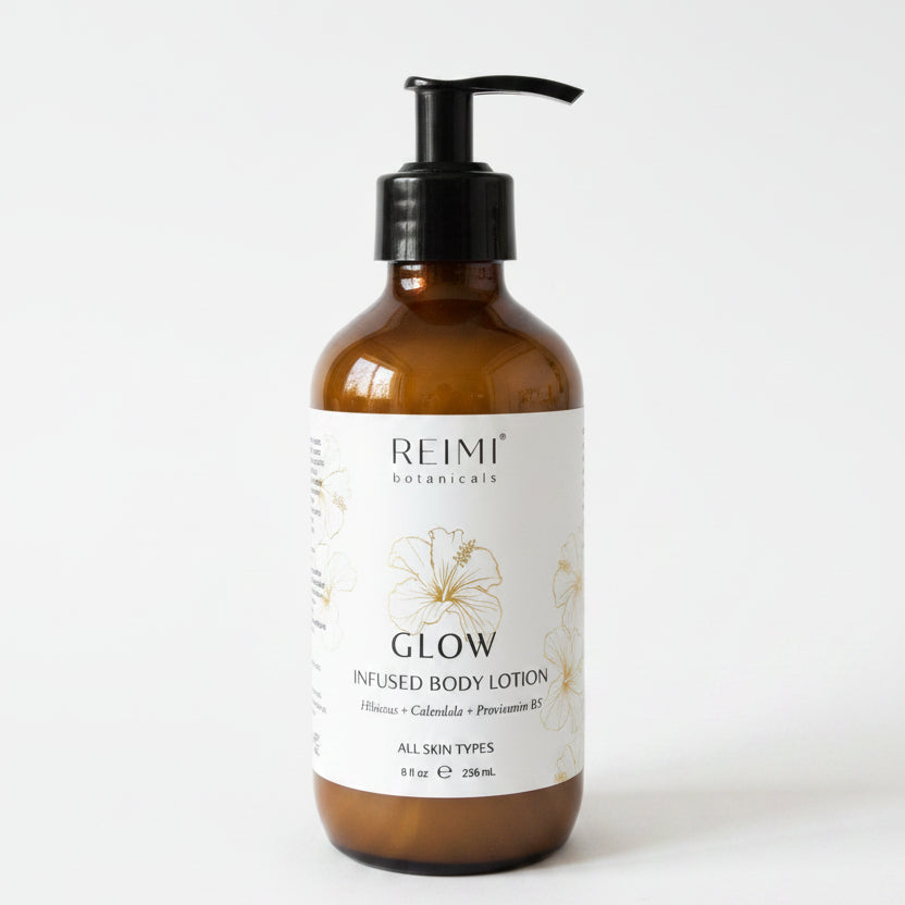 Brown bottle of Reimi Botanicals Glow infused body lotion on a white surface with a blurred background.