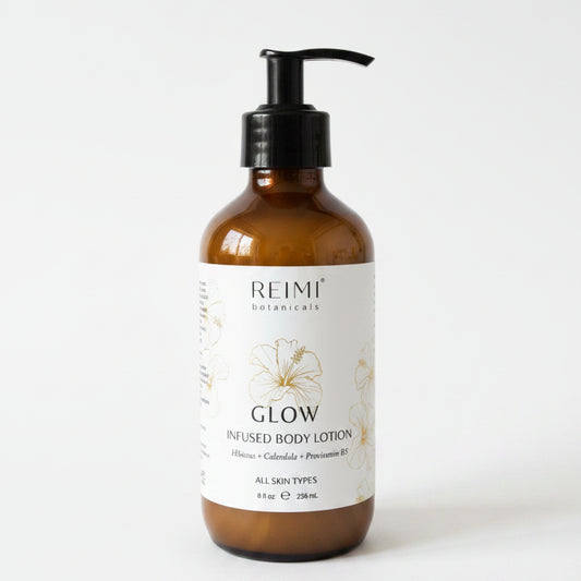 Brown bottle of Reimi Botanicals Glow infused body lotion on a white surface with a blurred background.