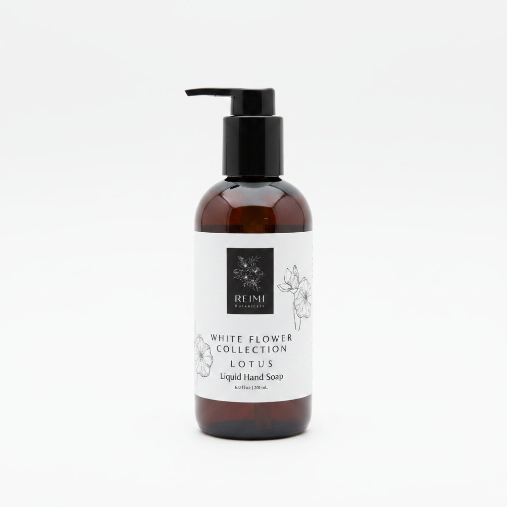 A dark glass bottle of liquid hand soap with a black pump dispenser and a white label reading 'White Flower Collection Lotus' by the brand REIMI, set against a white background.