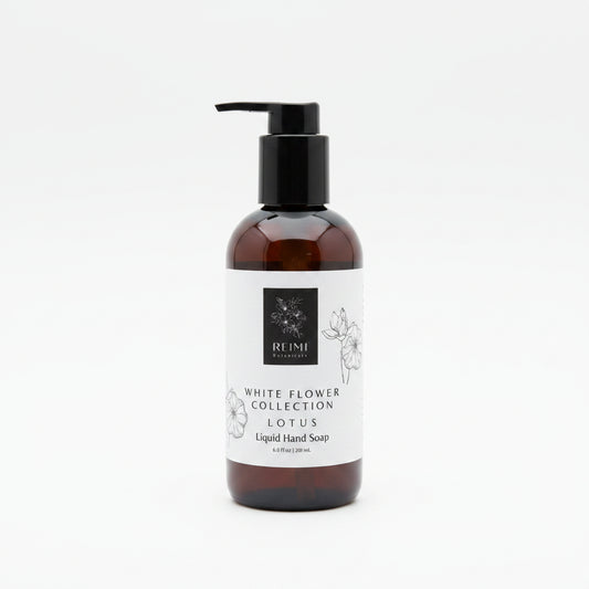 A dark glass bottle of liquid hand soap with a black pump dispenser and a white label reading 'White Flower Collection Lotus' by the brand REIMI, set against a white background.