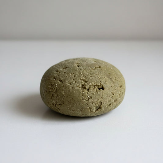 Round, earthy, greenish brown Face Cleansing + Polishing Bar