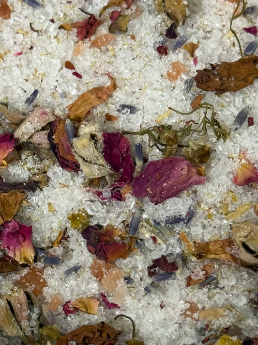 Close-up of a bath salt mix with flowers and herbs on a white background