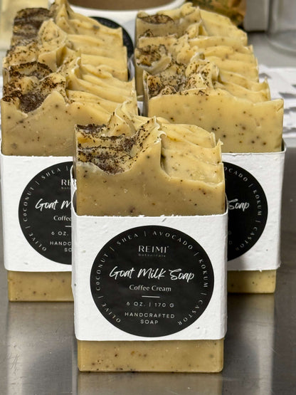 Handcrafted soap bars with visible coffee and shea butter, labeled 'REMI Goat Milk Soap Coffee Cream'.