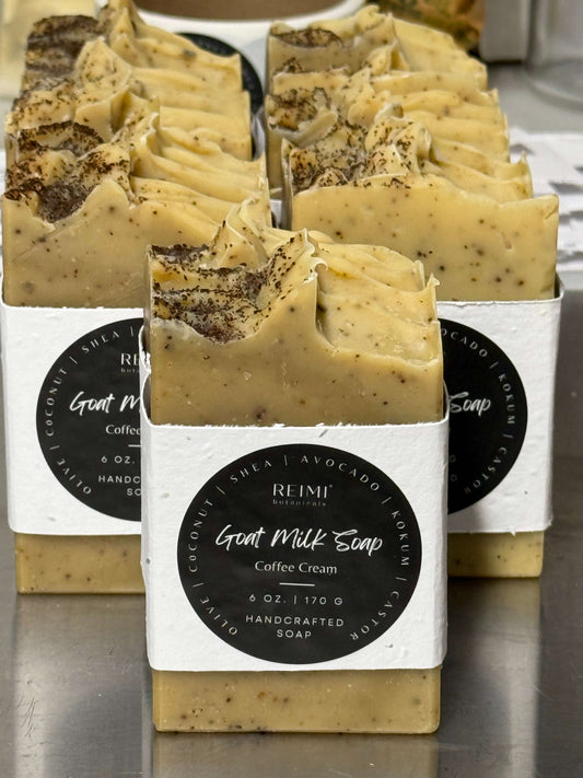 Handcrafted soap bars with visible coffee and shea butter, labeled 'REMI Goat Milk Soap Coffee Cream'.