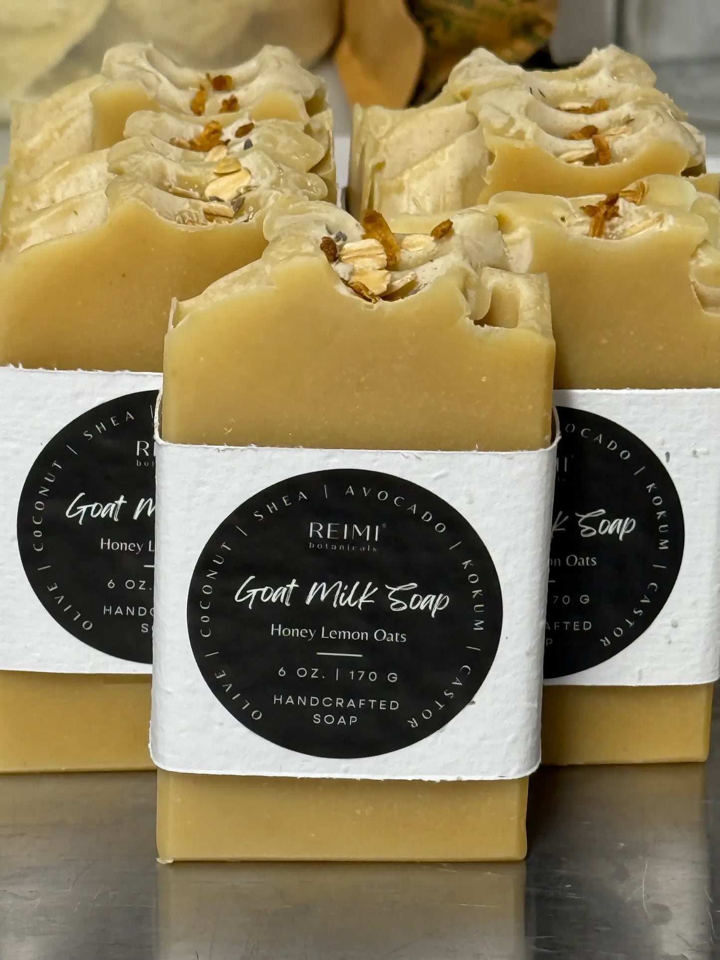 Handcrafted soap bars with visible ingredients on a reflective surface