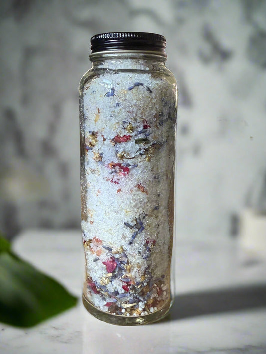 Glass jar filled with colorful bath salts on a marble surface