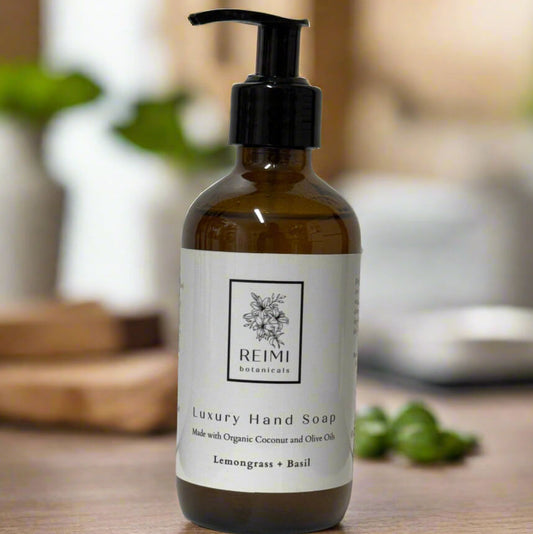 Bottle of Reimi Botanicals luxury hand soap on a wooden surface with a blurred background