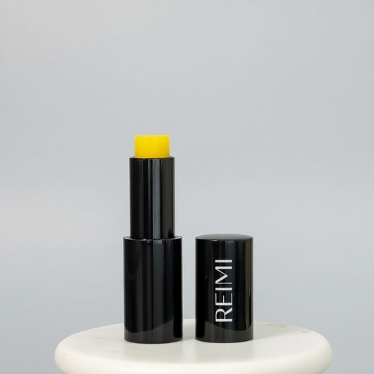 Black Lip stick with yellow top on a gray background