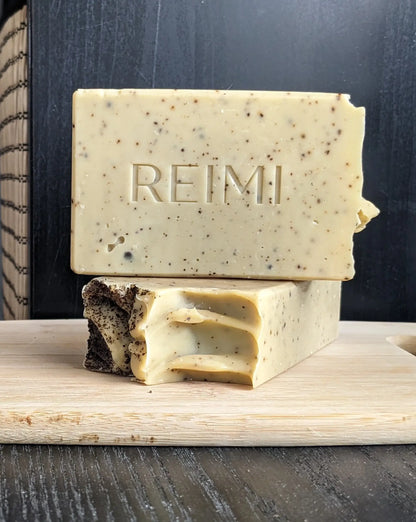 Bar of soap with 'REIMI' branding on a wooden block against a dark background